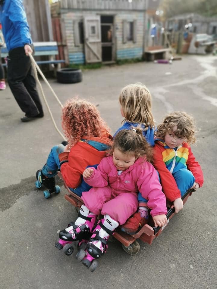 Four children are enjoying being pulled around on a bread tray with castors